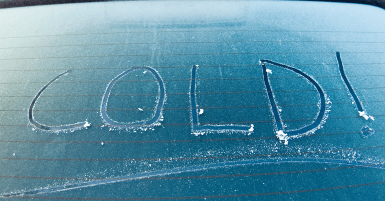 Cold! written into the frost on a car windshield